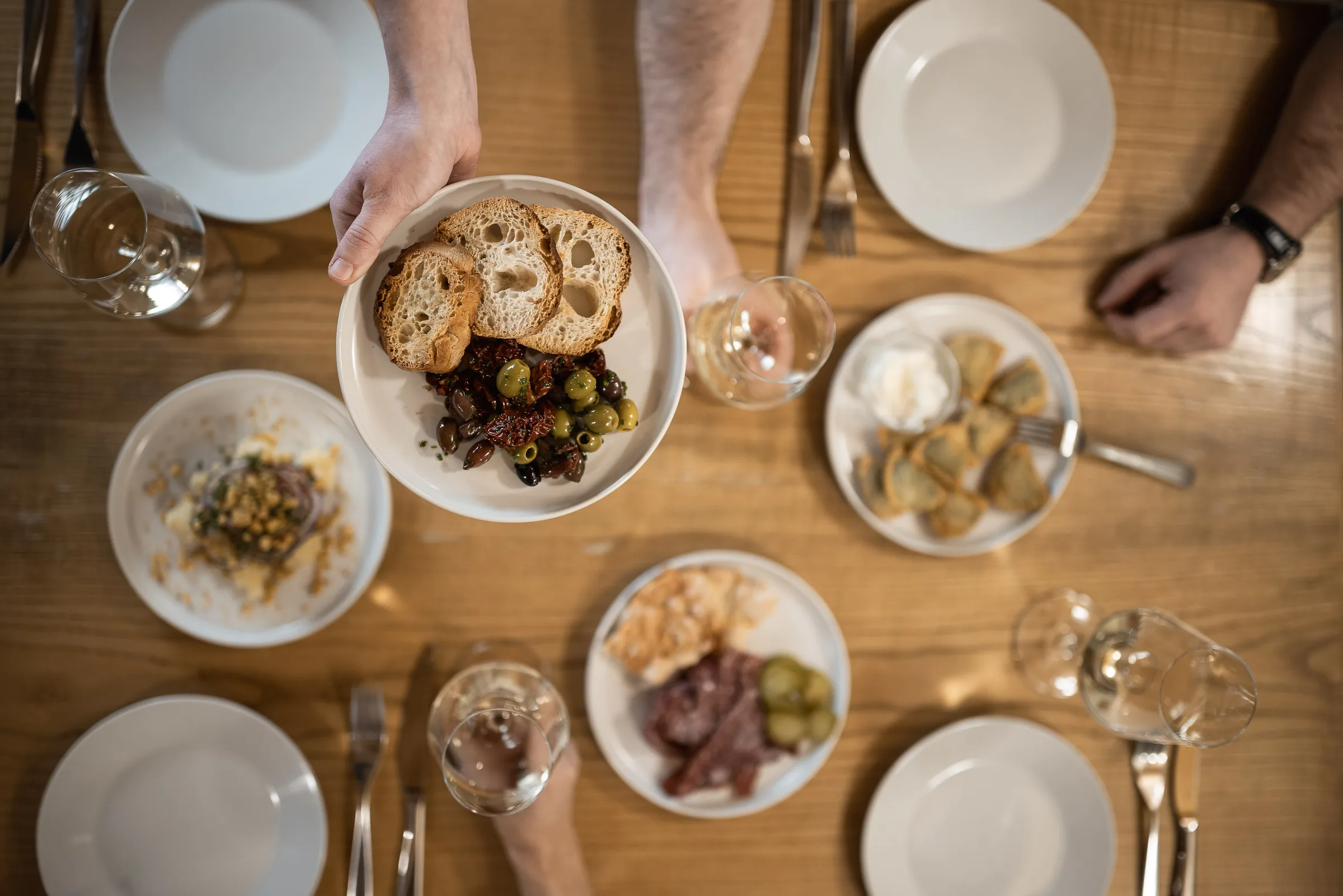 Gedeckte Tafel im Dorfgasthaus zur Linde von oben, eine Vorspeise mit Brot und Oliven wird serviert